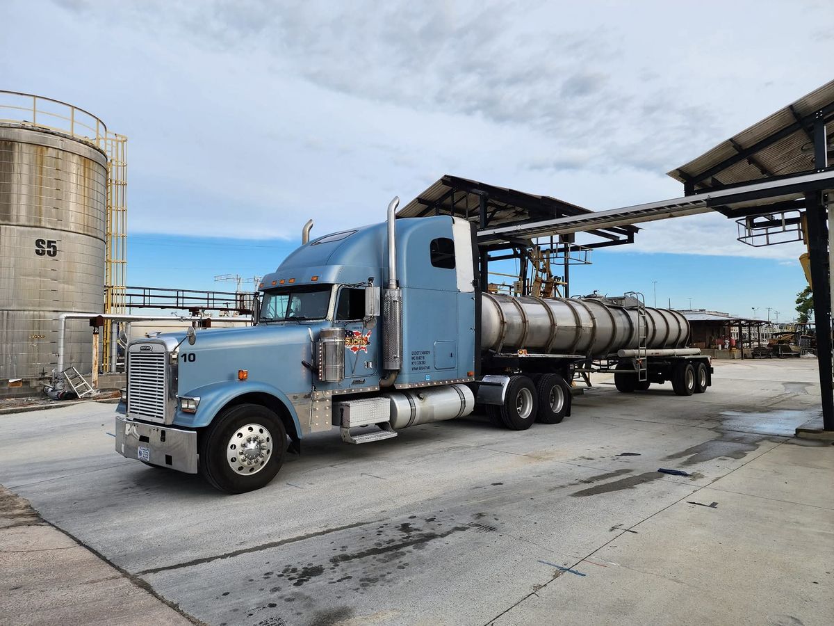 Light-blue Freightliner Classic, truck 10, with a stainless tanker trailer at a terminal
